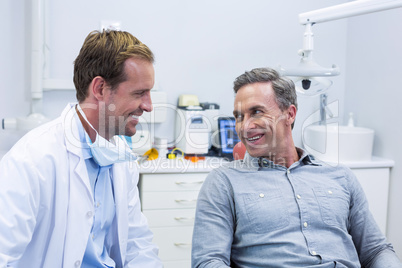 Smiling dentist and patient interacting with each other