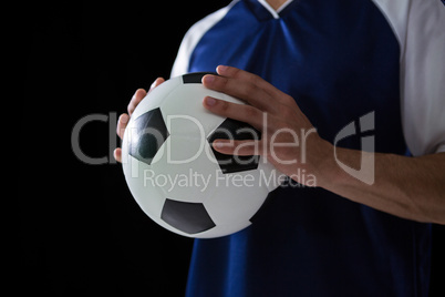 Mid-section of football player holding football with both hands