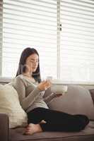Side view of woman using mobile phone while sitting on sofa
