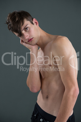 Shirtless androgynous man posing with hand on face