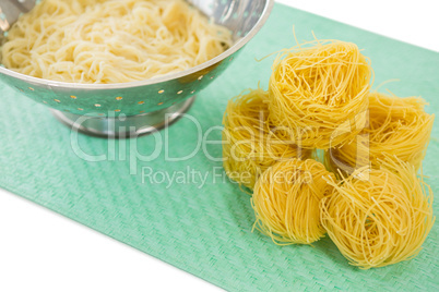 High angle view of pasta in colander with tagliolini on place mat