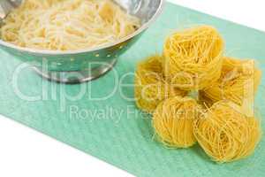 High angle view of pasta in colander with tagliolini on place mat