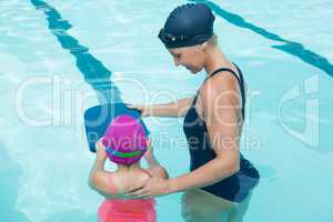 Female instructor training young girl in pool