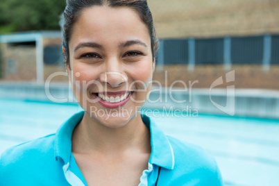 Smiling female coach standing near poolside