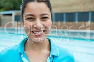 Smiling female coach standing near poolside