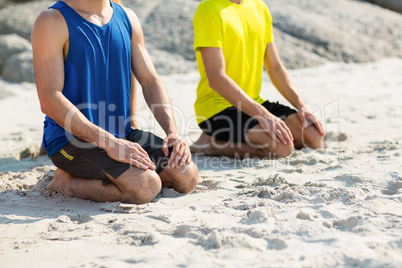 Friends in sports clothing kneeling on shore at beach