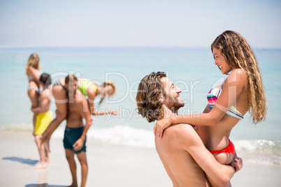 Smiling young man lifting woman at beach