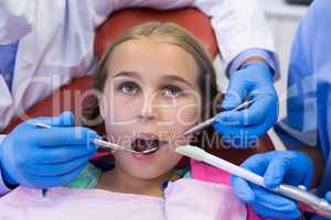Mid section of dentist and nurse examining a young patient with tools