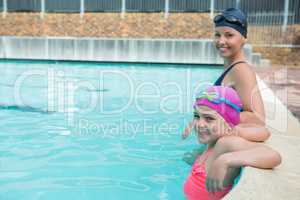 Female instructor and young girl relaxing in pool