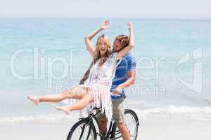 Couple enjoying while riding bicycle at beach
