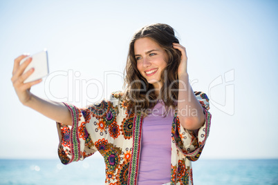 Woman smiling while taking selfie against sky