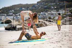 Woman balancing on knees of man at beach