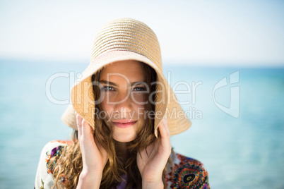 Portrait of young woman wearing hat while standing at beach