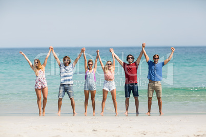 Friends holding hands with arms raised at beach