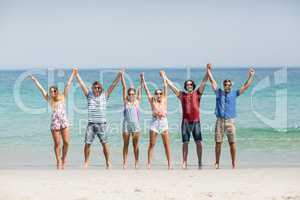Friends holding hands with arms raised at beach