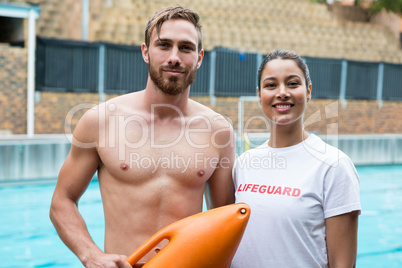 Two smiling lifeguards standing at poolside