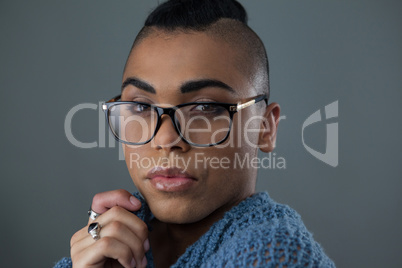 Transgender woman wearing eyeglasses over gray background