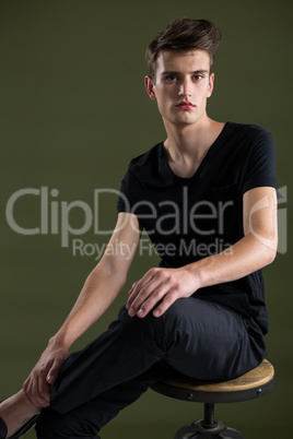 Androgynous man sitting on stool