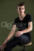 Androgynous man sitting on stool