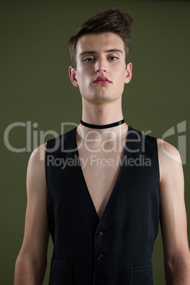 Androgynous man in waistcoat posing against green background