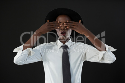 Androgynous man standing with his hands on eyes