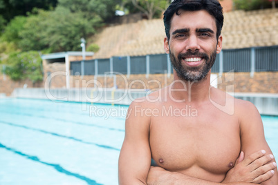 Smiling man standing with arms crossed near poolside