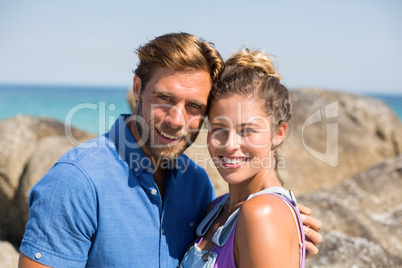 Smiling young couple against rocks at beach