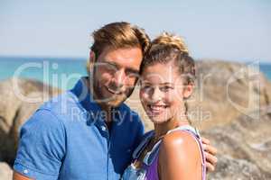 Smiling young couple against rocks at beach
