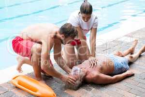 Lifeguards pressing chest of unconscious senior man