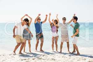 Young friends dancing at beach on sunny day