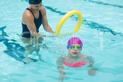 Female instructor training young girl in pool