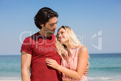 Couple with arm around standing on shore at beach