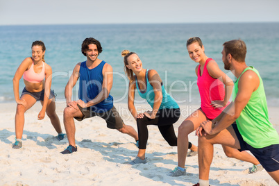 Happy friends stretching on shore at beach