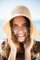 Portrait of happy young woman wearing hat at beach