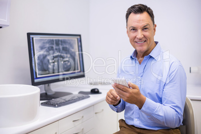 Portrait of happy dentist using mobile phone