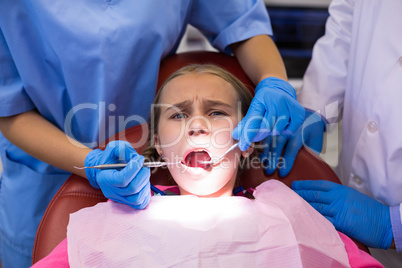 Dentist and nurse examining a young patient with tools