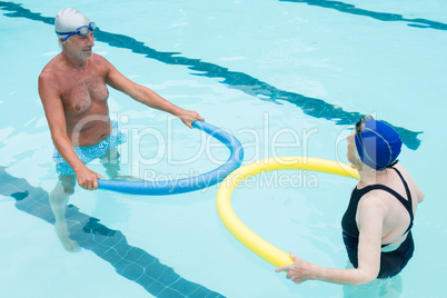 Senior couple exercising with pool noodle