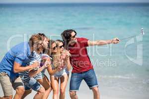 Cheerful friends taking selfie at beach