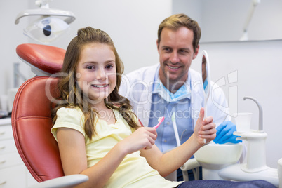 Smiling young patient holding mirror in in dental clinic