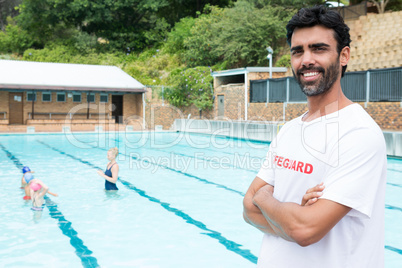 Smiling lifeguard standing with arms crossed