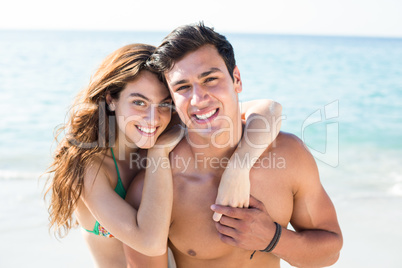Happy young couple standing on shore at beach