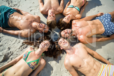 Happy friends sunbathing on shore at beach