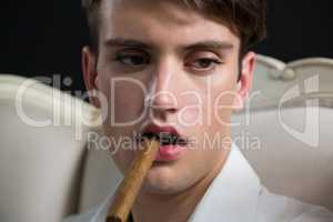 Androgynous man posing with cigar in his mouth
