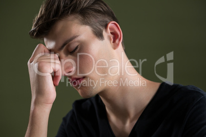Tense androgynous man with hand on forehead
