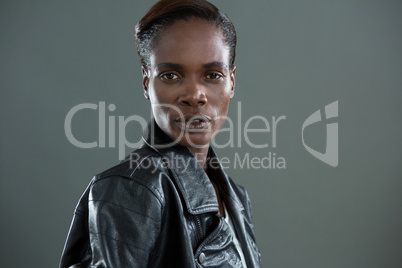 Androgynous man in black jacket posing against grey background