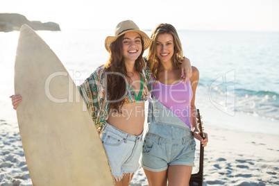 Friends with surfboard and guitar on shore at beach