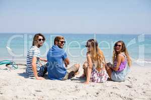 Cheerful friends sitting on shore during sunny day