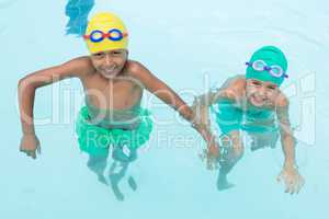 Two smiling kids swimming in the pool