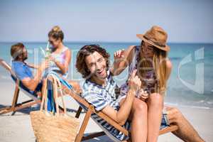 Romantic young couples sitting on deck chairs at beach
