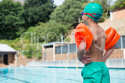 Boy wearing arm band standing at poolside